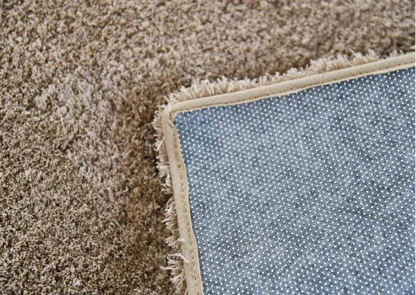 Corner-of-plush-brown-carpet-showing-anti-slip-backing