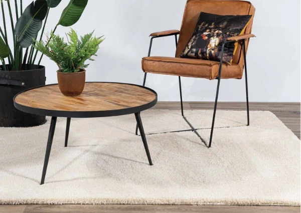 Cream-area-rug-under-a-round-wood-table-and-leather-chair