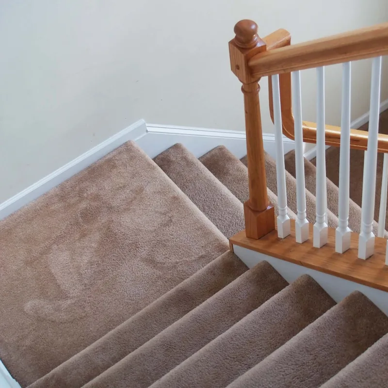 Plush tan carpet installed on staircase steps.